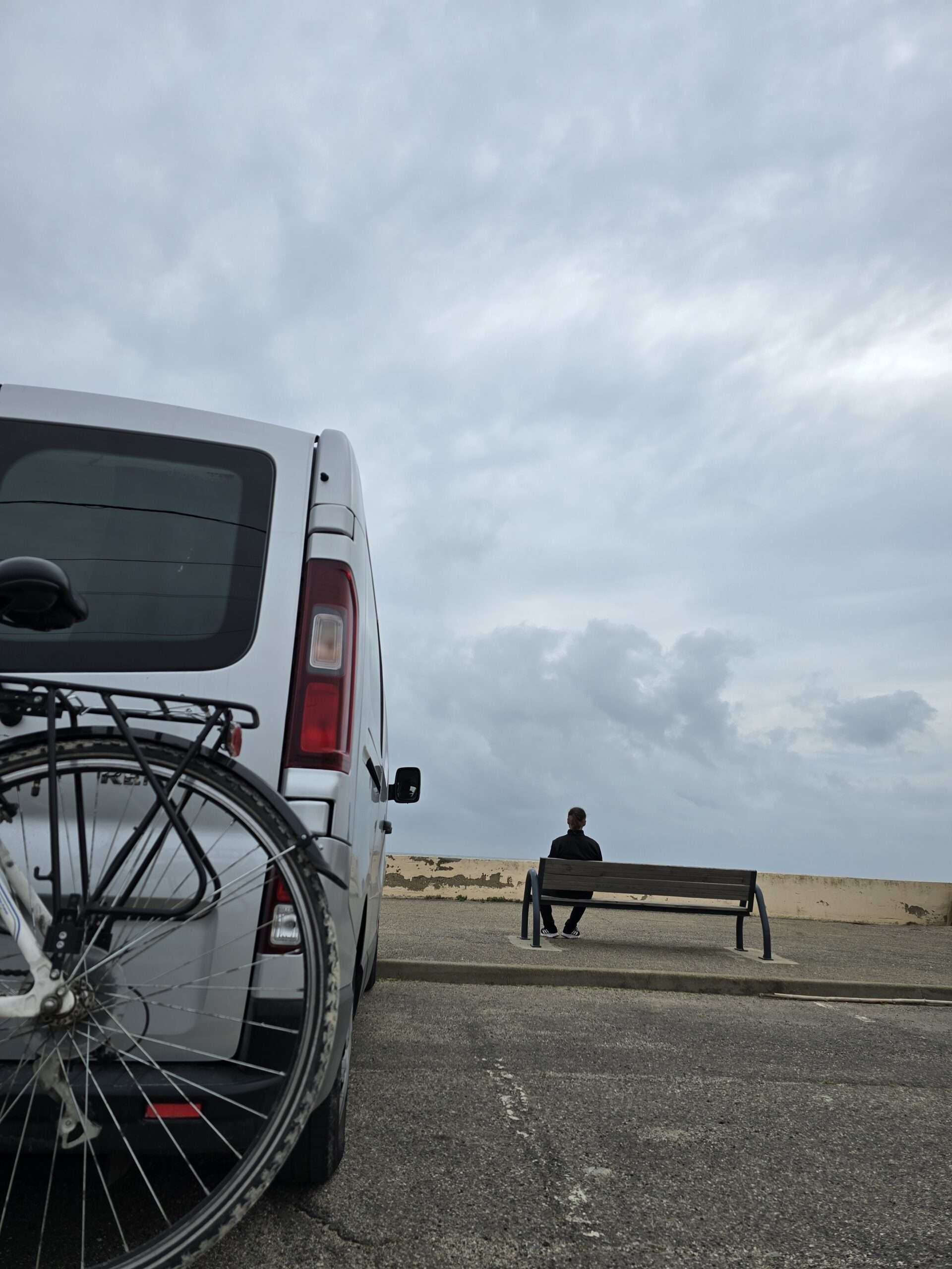 Samochód na plaży. Mężczyzna siedzący i dumający na ławce